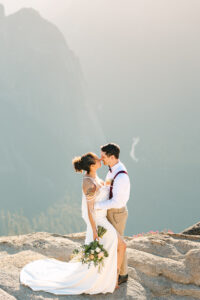 Bride and Groom embracing and holding each other at Taft Point while they over look dramatic cliffsides above the Yosemite Valley