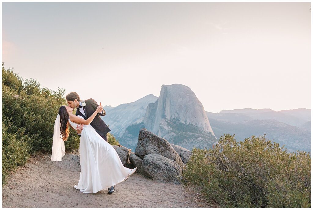 Bride and groom sharing a romantic kiss at Glacier Point in Yosemite, with Half Dome in the background