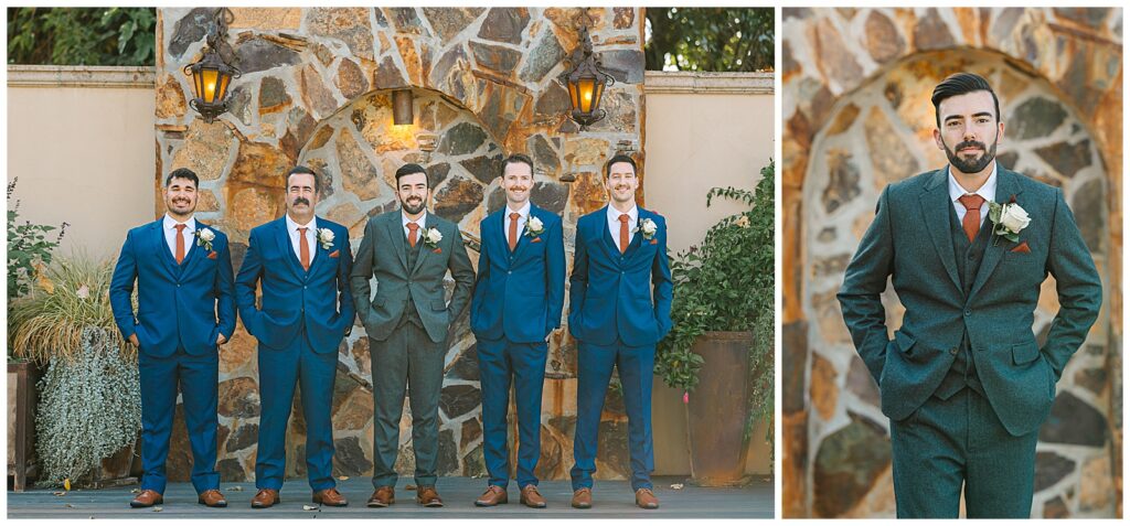 groom posing with his guys in royal blue suits while the groom wears a wool blue/gray suit in front of a brick wall