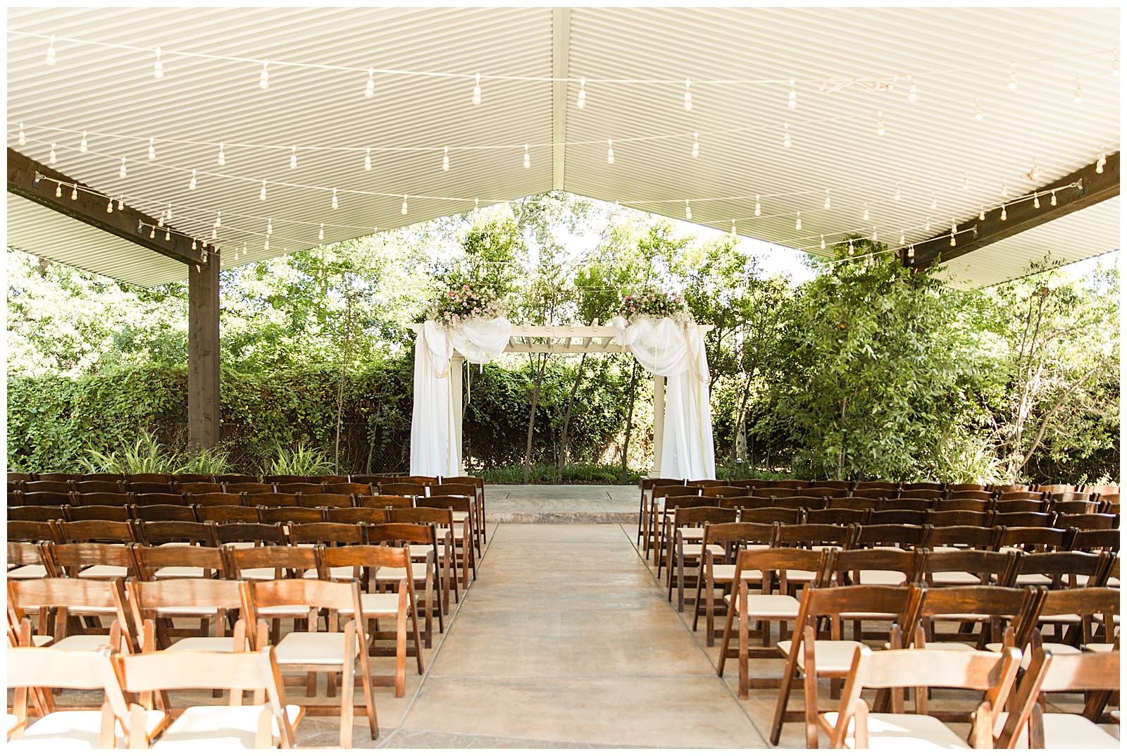 Ceremony space at the historic seven sycamores ranch with folding brown wood chairs, bistro lights, and lilac florals