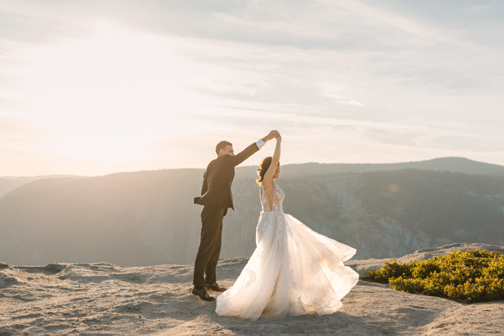 Bride and Groom dancing cliffside at Taft Point. Brides dress is twirling in the sunlight.