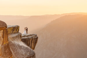 Bride and Groom saying their vows while holding hands on the cliffside at Taft Point overlooking the Yosemite Valley