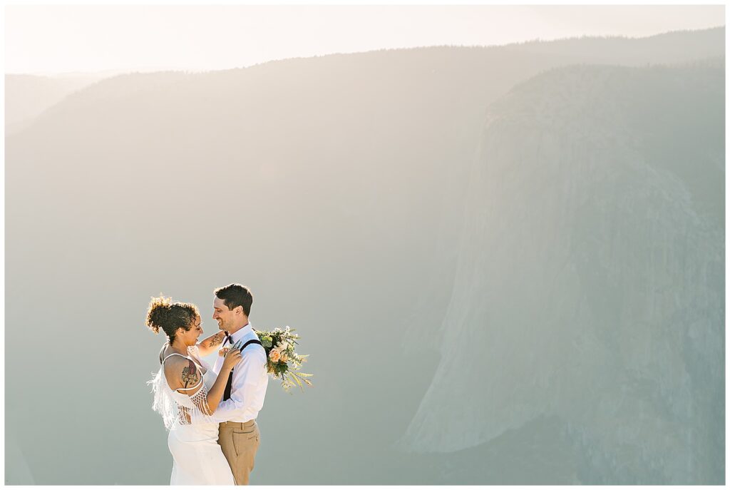 A couple embracing at sunset during their intimate Yosemite elopement, surrounded by the majestic landscape and soft, glowing light, capturing the beauty amidst the Yosemite crowds.